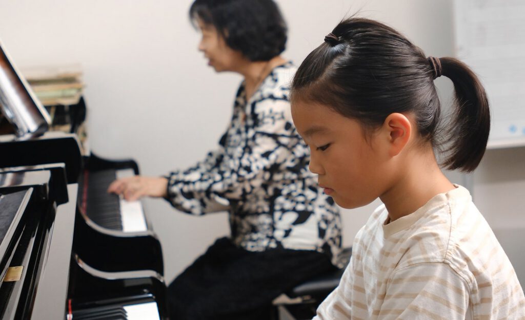 個人レッスンを受ける小学生とよしむらピアノ教室の吉村先生